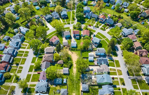 Aerial view of residential neighborhood showing mature trees in HOA and commercial properties.